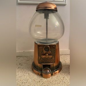 Pretty large gum ball machine. Copper tone to it.